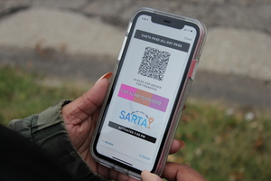 An image of a person holding a smartphone showing EZ-Fare mobile ticketing app.