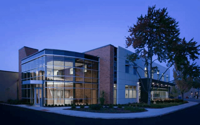 SARTA Gateway offices-A modern building with large glass windows and brick walls, lit up at night. A tree and a sidewalk are in front.
